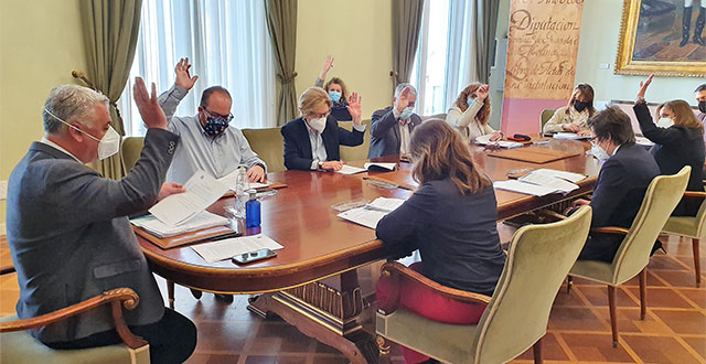 Foto de varias personas votando a mano alzada en una sala de juntas